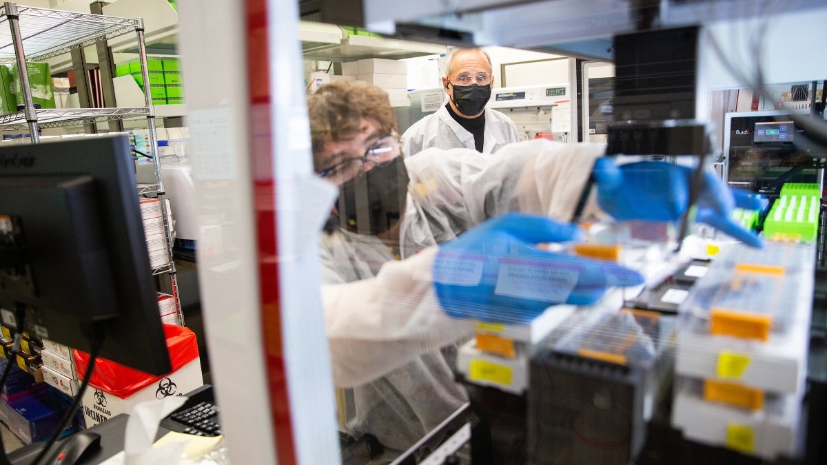 Two people working in a saliva testing lab