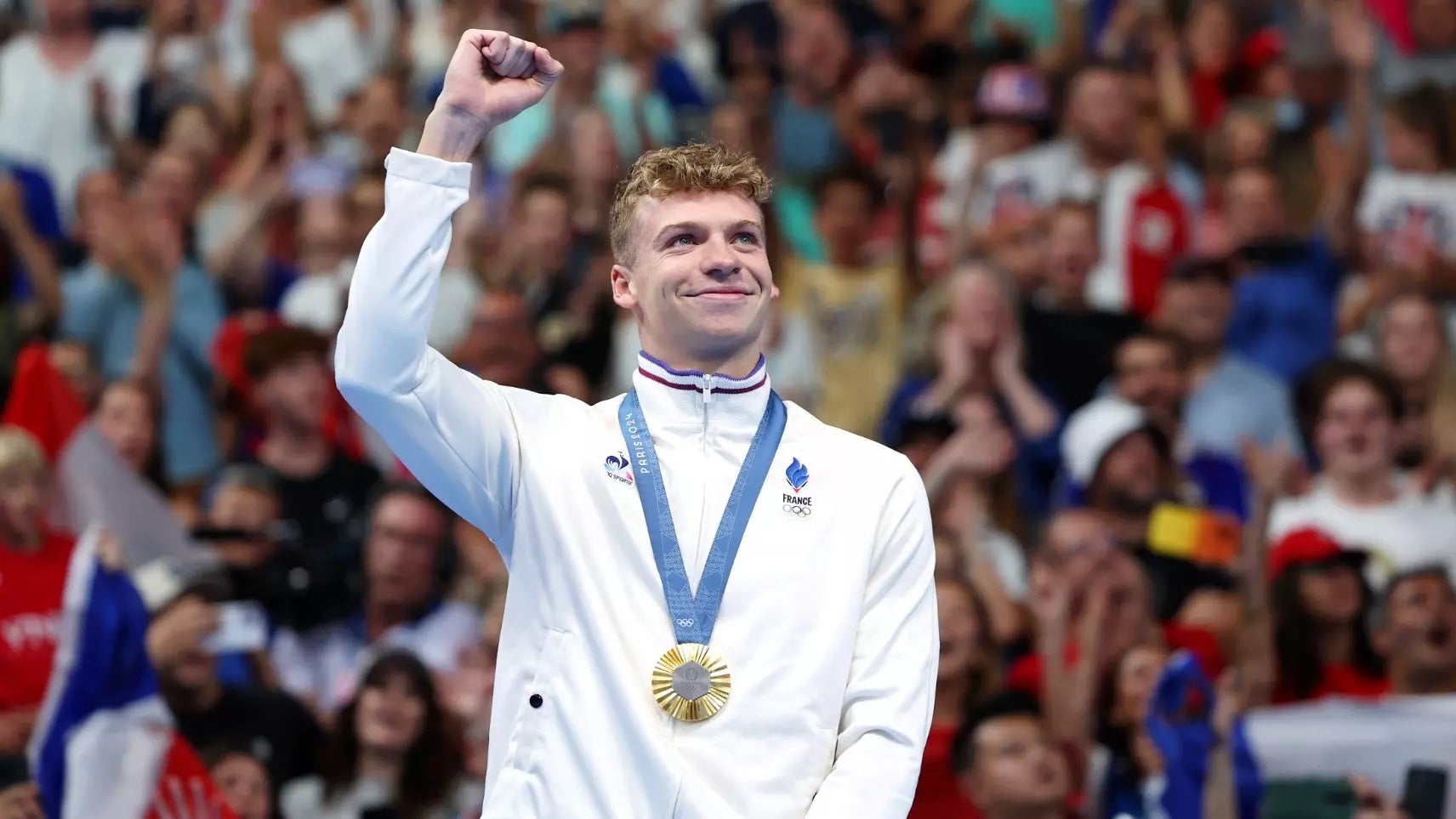 Sun Devil swimmer Leon Marchand raises his hand after winning a gold medal at the 2024 Olympic Games in Paris, France